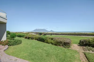a garden with a view of the ocean at Stylish Apartment with Ocean Views - Dolphin Beach in Cape Town