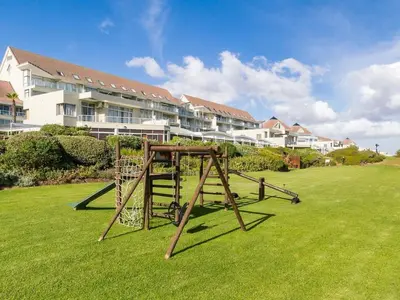 a playground in front of a large apartment complex at Studio Kiters Room - Dolphin Beach in Cape Town