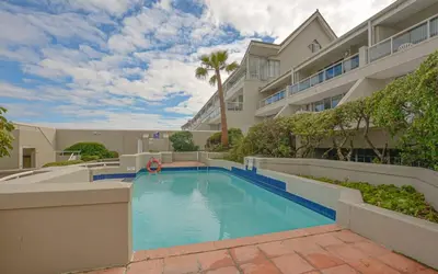 a swimming pool in front of a building at Studio Kiters Room - Dolphin Beach in Cape Town