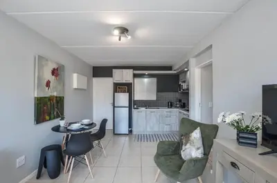 a kitchen and living room with a table and chairs at Modern 1 Bedroom Apartment in Blouberg in Cape Town