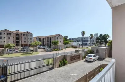 a balcony with a car parked on a street at Modern 1 Bedroom Apartment in Blouberg in Cape Town