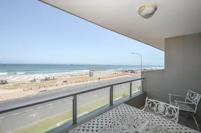a balcony with a table and a view of the beach at 3 Bedroom Apartment - Stunning Ocean Views in Cape Town