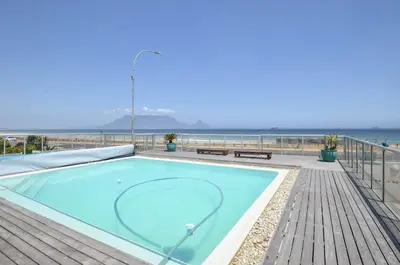 a swimming pool with the ocean in the background at 3 Bedroom Apartment - Stunning Ocean Views in Cape Town