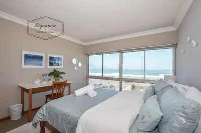 a bedroom with a bed and a desk and a window at 2 Bedroom Apartment - Zeezicht Blouberg in Cape Town