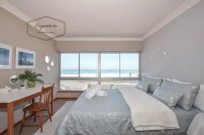 a bedroom with a bed and a desk and a table with a window at 2 Bedroom Apartment - Zeezicht Blouberg in Cape Town