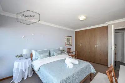 a bedroom with a large bed and a table at 2 Bedroom Apartment - Zeezicht Blouberg in Cape Town