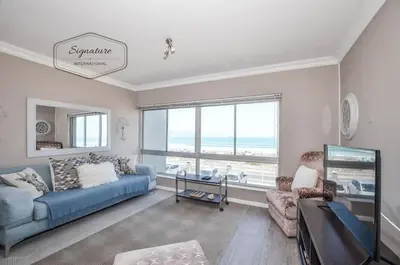 a living room with a blue couch and a large window at 2 Bedroom Apartment - Zeezicht Blouberg in Cape Town