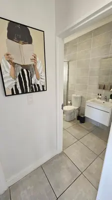 a bathroom with a toilet and a person reading a newspaper at Luxury Apartment in Somerset West in Strand