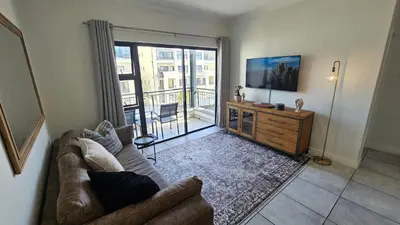 a living room with a couch and a television at Luxury Apartment in Somerset West in Strand