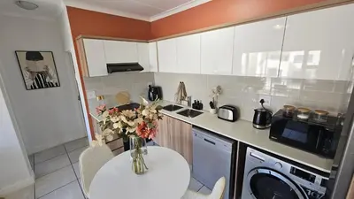 a kitchen with a vase of flowers on a table at Luxury Apartment in Somerset West in Strand