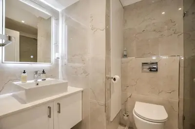 a bathroom with a sink and a toilet and a mirror at Modern 2 Bedroom Apartment At Dolphin Beach in Cape Town