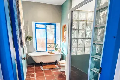 a bathroom with a tub and a toilet and a window at Amulet At The Sea in Hermanus