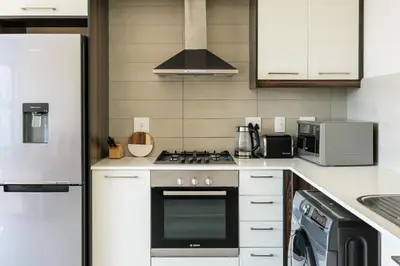 a kitchen with a stove top oven next to a refrigerator at Canalside Tranquility in Cape Town