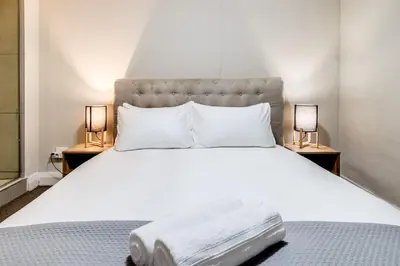 a bedroom with a large white bed with two lamps at Canalside Tranquility in Cape Town