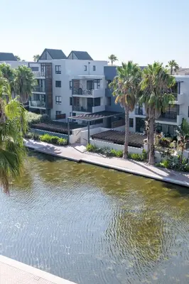 a river with palm trees in front of condos at Canalside Tranquility in Cape Town