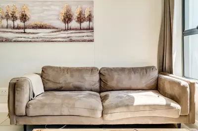 a couch in a living room with a picture of trees at Canalside Tranquility in Cape Town
