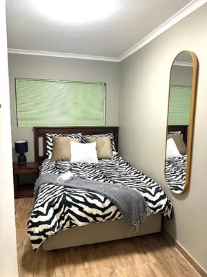 a bedroom with a zebra print bed and a mirror at 29 Windsor Flatlet 2 in Silver Sands