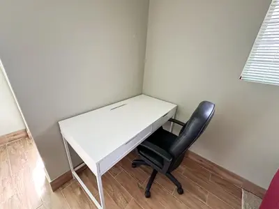 a white desk and a black chair in a room at 29 Windsor Flatlet 2 in Silver Sands