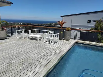 a deck with two chairs next to a swimming pool at Chanteclair Holiday Home in Hermanus