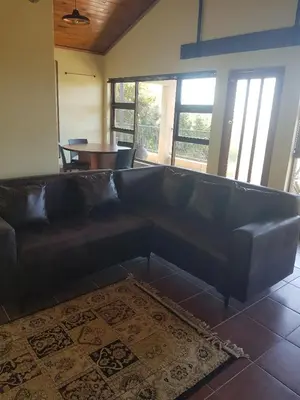 a black leather couch in a living room with a table at 4 th On Boundary in Gordonʼs Bay