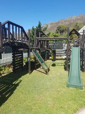 a wooden playground with a slide and swings at 4 th On Boundary in Gordonʼs Bay