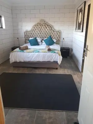 a bedroom with a large bed with blue pillows at 4 th On Boundary in Gordonʼs Bay