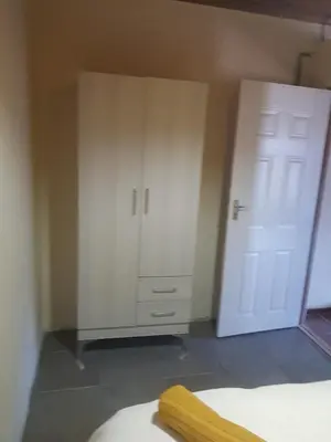 a bedroom with a closet and a white cabinet at 4 th On Boundary in Gordonʼs Bay