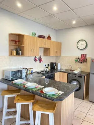 a kitchen with a counter with two stools and a counter top at Granaat Pit - Paarl - Self Catering Apartment in Paarl