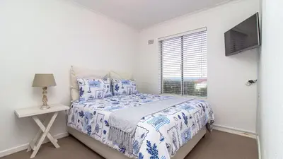 a white bedroom with a bed and a window at 258 Hermanus Beach club in Hermanus