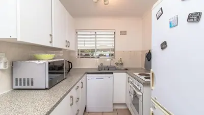 a white kitchen with white cabinets and a microwave at 258 Hermanus Beach club in Hermanus