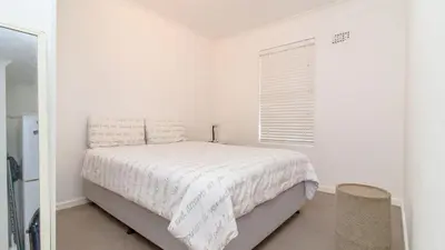 a white bedroom with a bed and a window at 258 Hermanus Beach club in Hermanus
