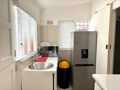 a small kitchen with a sink and a refrigerator at Private Flatlet B in Goodwood