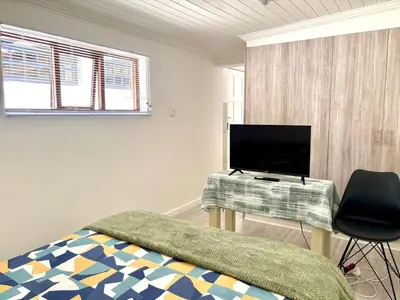 a bedroom with a bed and a desk with a television at Private Flatlet B in Goodwood