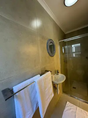 a bathroom with a sink and a shower and towels at Ocean Whisper Room 6 minutes away from the beach in Cape Town