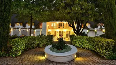 a large white house with a garden in front of it at Le Franschhoek Hotel & Spa by Dream Resorts in Franschhoek