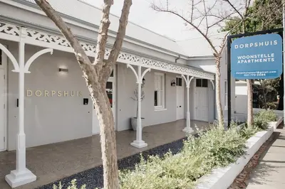 a white building with a sign in front of it at Dorpshuis Apartment, Main Street, Paarl in Paarl