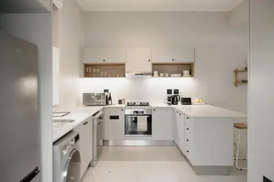 a white kitchen with white cabinets and appliances at Dorpshuis Apartment, Main Street, Paarl in Paarl