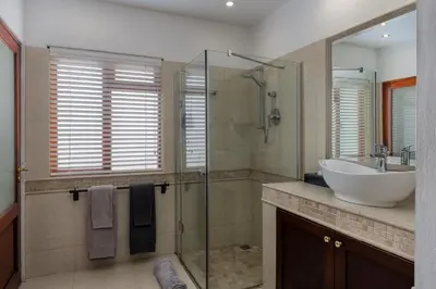 a bathroom with a sink and a glass shower at Apricot Gardens Guesthouse in Gordonʼs Bay