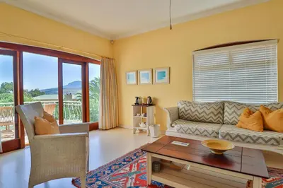 a living room with a couch and a table at Apricot Gardens Guesthouse in Gordonʼs Bay