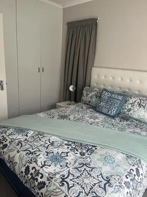 a bedroom with a bed with a blue and white comforter at 46 Atlanta - A Home away from Home in Strand
