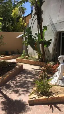 a garden with a white statue in front of a building at Spacious Self-Catering Apartment with Private Entrance in Peaceful Paradyskloof, Stellenbosch in Stellenbosch