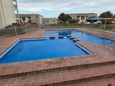 a large swimming pool with blue water in a building at Unit 169 Hermanus Beach Club in Hermanus