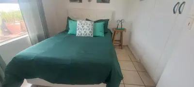 a bedroom with a bed with a green comforter and a window at Unit 169 Hermanus Beach Club in Hermanus