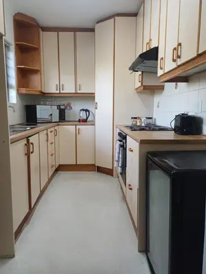 a kitchen with white cabinets and a black appliance at Greens Golf Course Apartment in De Grendel
