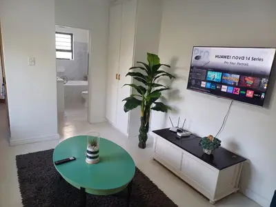 a living room with a table and a tv on the wall at Greens Golf Course Apartment in De Grendel