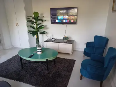 a living room with a table and two blue chairs at Greens Golf Course Apartment in De Grendel