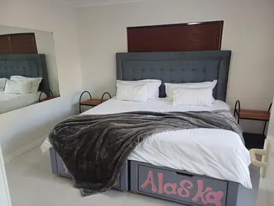 a bedroom with a large bed with white sheets at Greens Golf Course Apartment in De Grendel