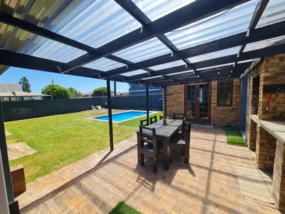 a pergola with a table and bench on a patio at Kuku House in Cape Town