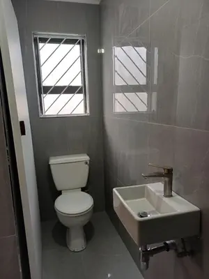 a bathroom with a toilet and a sink and a window at Halaal Serenity 3bedroom 6sleeper in Cape Town