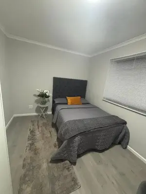 a bedroom with a bed with an orange pillow at Tranquil Luxe Retreat in Cape Town